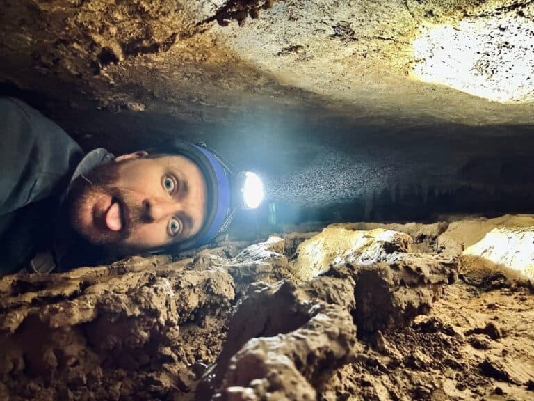 A Guy squeezing through a cave passage