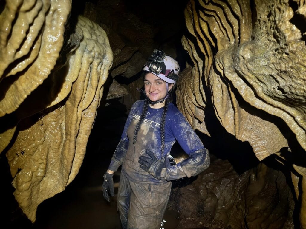A caver posing for a photo surrounded by cave bacon