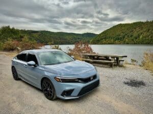 A car parked next to a lake and picnic table