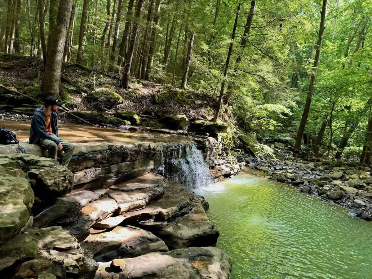 Someone sitting on the edge of a small waterfall